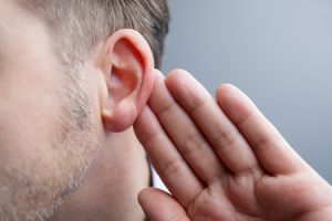 man with hand on ear listening for quiet sound or paying attention